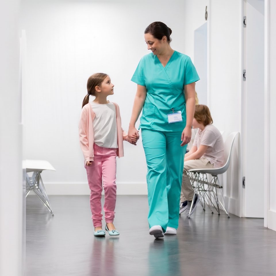 Enfermera de pediatría caminando de la mano de una niña por el pasillo del hospital
